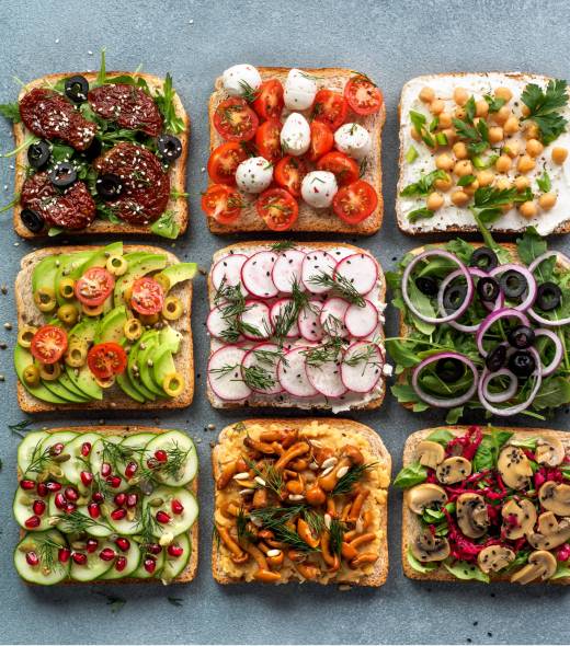 Assortment vegan sandwiches on gray stone background. Set different vegetarian smorrebrod. Top view or flat lay.